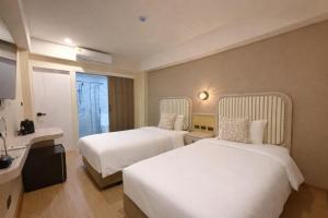 a hotel room with two beds and a sink at Ranana Bangkok in Bangkok
