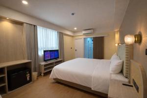 a bedroom with a white bed and a television at Ranana Bangkok in Bangkok