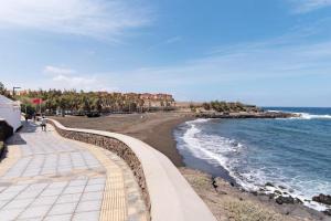 a beach with a black sand and the ocean at Pablo House Beach in Telde