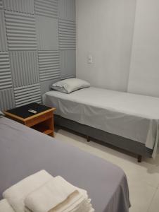 two beds in a small room with a table and a bed at Edícula 55m2, aceita pequenos pets in Foz do Iguaçu +41 photos