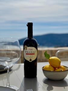a bottle of wine next to a bowl of lemons and a glass at Luxury stone house with infinity pool in Herceg-Novi +23 photos