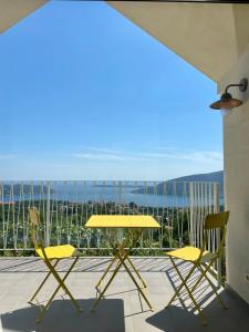 a yellow table and chairs on a balcony with a view at Luxury stone house with infinity pool in Herceg-Novi