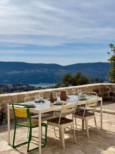 a white table and chairs with wine glasses on it at Luxury stone house with infinity pool in Herceg-Novi
