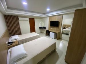 a hotel room with two beds and a television at Tawfiqs Hotel in Barra do Garças +42 photos