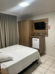 a bedroom with a bed and a flat screen tv at Hotel Comodoro in Vilhena +23 photos
