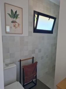 a bathroom with a window above a toilet at Le Studio Joli in La Possession
