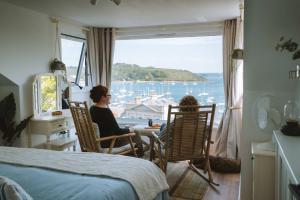 a woman sitting in a chair in a room with a window at Tide View Townhouse - By Rowes Retreats in Falmouth