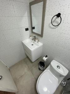 a bathroom with a white toilet and a sink at Tayka Suite in La Serena +6 photos