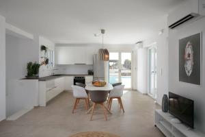 a kitchen with white cabinets and a table and chairs at Villa Salt in Naxos Chora