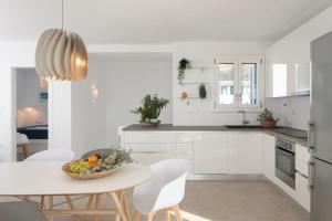a white kitchen with a table and white chairs at Villa Salt in Naxos Chora +42 photos