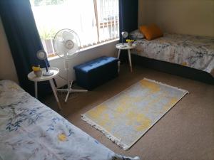 a bedroom with two beds and a fan and a rug at Mimosa House Twin Room in Brackenfell +5 photos