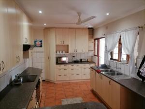 a kitchen with white cabinets and black counter tops at Mimosa House Twin Room in Brackenfell
