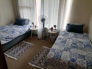 a bedroom with two beds and a fan and a window at Mimosa House Twin Room in Brackenfell