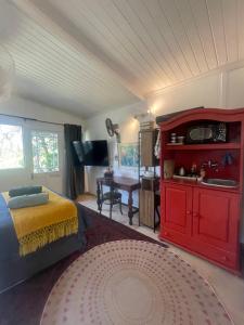 a bedroom with a bed with a red cabinet and a desk at Waterberry Hideaway in Pringle Bay