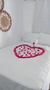 a white bed with a heart of roses on it at Pousada recanto do sol in Cajueiro