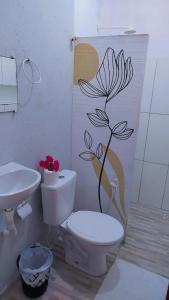 a bathroom with a toilet and a flower on the wall at Pousada recanto do sol in Cajueiro