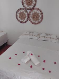 a bed with roses on it with a white sheet at Pousada recanto do sol in Cajueiro