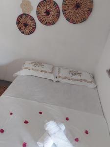 a white bed with two pillows and flowers on it at Pousada recanto do sol in Cajueiro