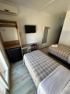 ein Hotelzimmer mit zwei Betten und einem Flachbildfernseher in der Unterkunft Veneto Hotel in Canguçu