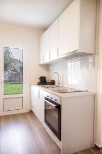 a kitchen with white cabinets and a sink and a stove at Tailor Garden House in Tríkala