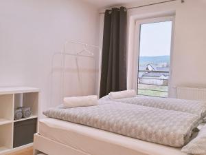 a white bedroom with two beds and a window at Vila Hafira in Zuberec