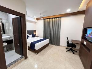 a bedroom with a bed and a tv and a bathroom at Nyotel-MP Nagar Bhopal in Bhopal