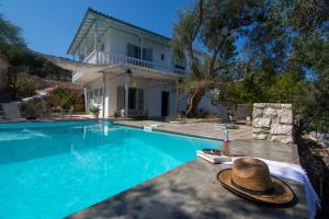 a villa with a swimming pool with a hat next to it at New! Paxosblue suites sea view with private pool in Gaios