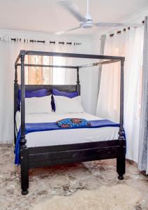 a bedroom with a black canopy bed with blue pillows at Kilifi Tulivu in Kilifi