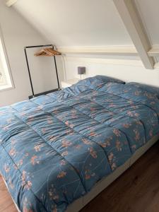 a bed with a blue comforter in a room at Het Korenhuus in Lewedorp