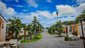 a gravel road with tables and benches in a courtyard at บลูคริสตัลรีสอร์ทแหลมสิงห์ in Laem Sing