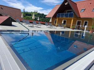 a swimming pool with chairs and a house in the background at Weingut-Gästezimmer UHL in Ratsch an der Weinstraße