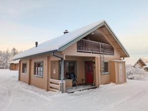 a wooden cabin with a red door in the snow at Matkailumaja Heikkala Cottages in Ruka +29 photos