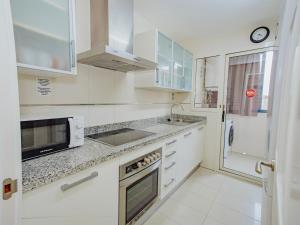 a white kitchen with a sink and a microwave at Apartamento Gema Gemelos 26 in Benidorm