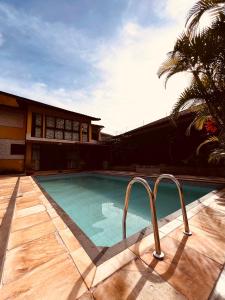 a swimming pool next to a house with a palm tree at Mansão Bardo in Petrópolis