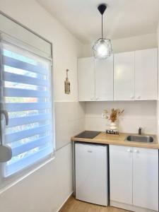 a kitchen with white cabinets and a sink and a window at Danin apartmani in Bar