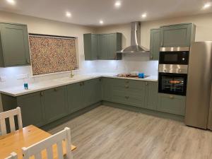 a kitchen with green cabinets and a table and a refrigerator at St Magnus Retreat in Lerwick