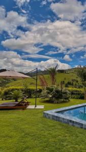 a backyard with a swimming pool and an umbrella at Chalé RIVAGI in Passa Quatro