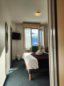 a hotel room with a bed and a window at Hotel Au Val Doré in La Bourboule