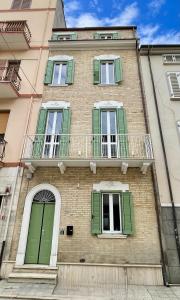 a building with green shutters and a balcony at Affittacamere Casa Florens Guest House in San Benedetto del Tronto