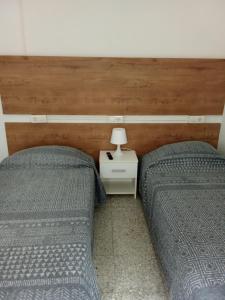 a bedroom with two beds and a table with a lamp at Casa ADOLFO in Almáciga