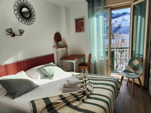 a bedroom with a bed and a balcony with a view at Hotel Au Val Doré in La Bourboule