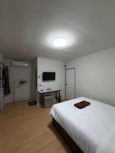 a bedroom with a white bed and a television at Greenview Room and Restaurant in Ko Yao Yai