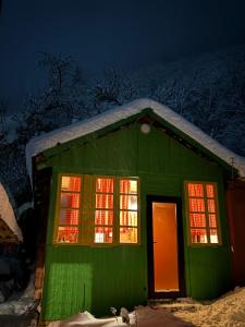 a green house with lights in the windows at night at Dzveli kokhi in Utsera