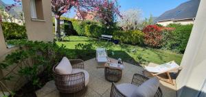 a patio with chairs and tables and a yard at Maison des Hortensias in Saint-Contest