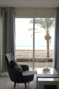 a living room with a chair and a view of the beach at voya hotel and suites in Soûr