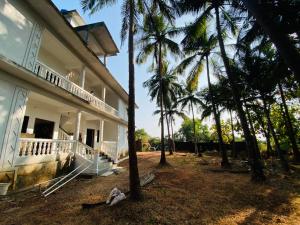 a building with palm trees in front of it at HoneyBee 2BHK Homestay Agonda in Agonda
