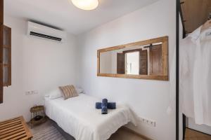 a white bedroom with a bed and a mirror at Ca Sa Joia - Beautiful Views in Port d'Andratx
