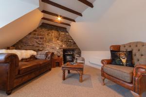 a living room with leather furniture and a stone wall at Sea Crest - Beachfront Escape with Whisky Snug in Cullen