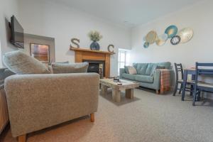 a living room with a couch and a table at Sea Crest - Beachfront Escape with Whisky Snug in Cullen