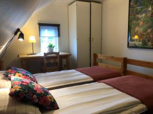 two beds in a bedroom with a desk and a window at Håverud Hostel in Håverud